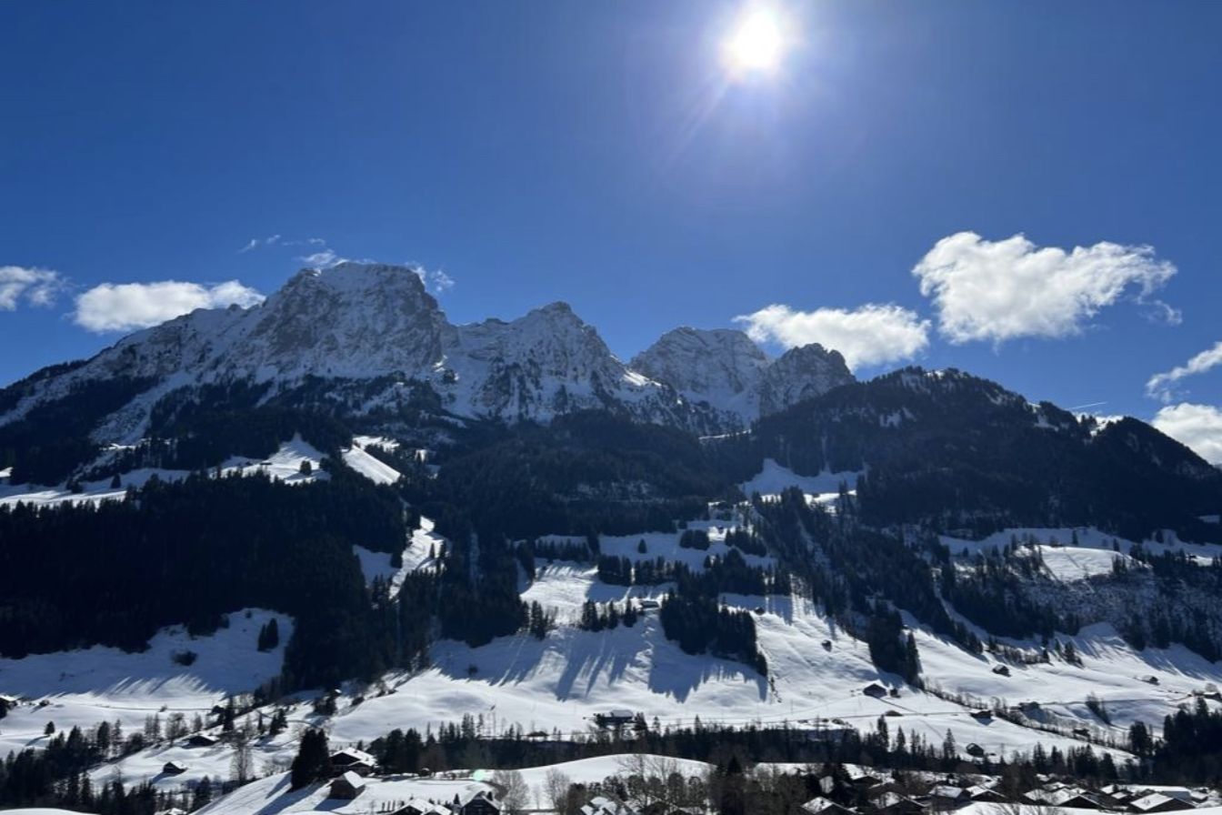 Rougemont in winter: snow-covered meadows and chalets below sunlit rocky peaks